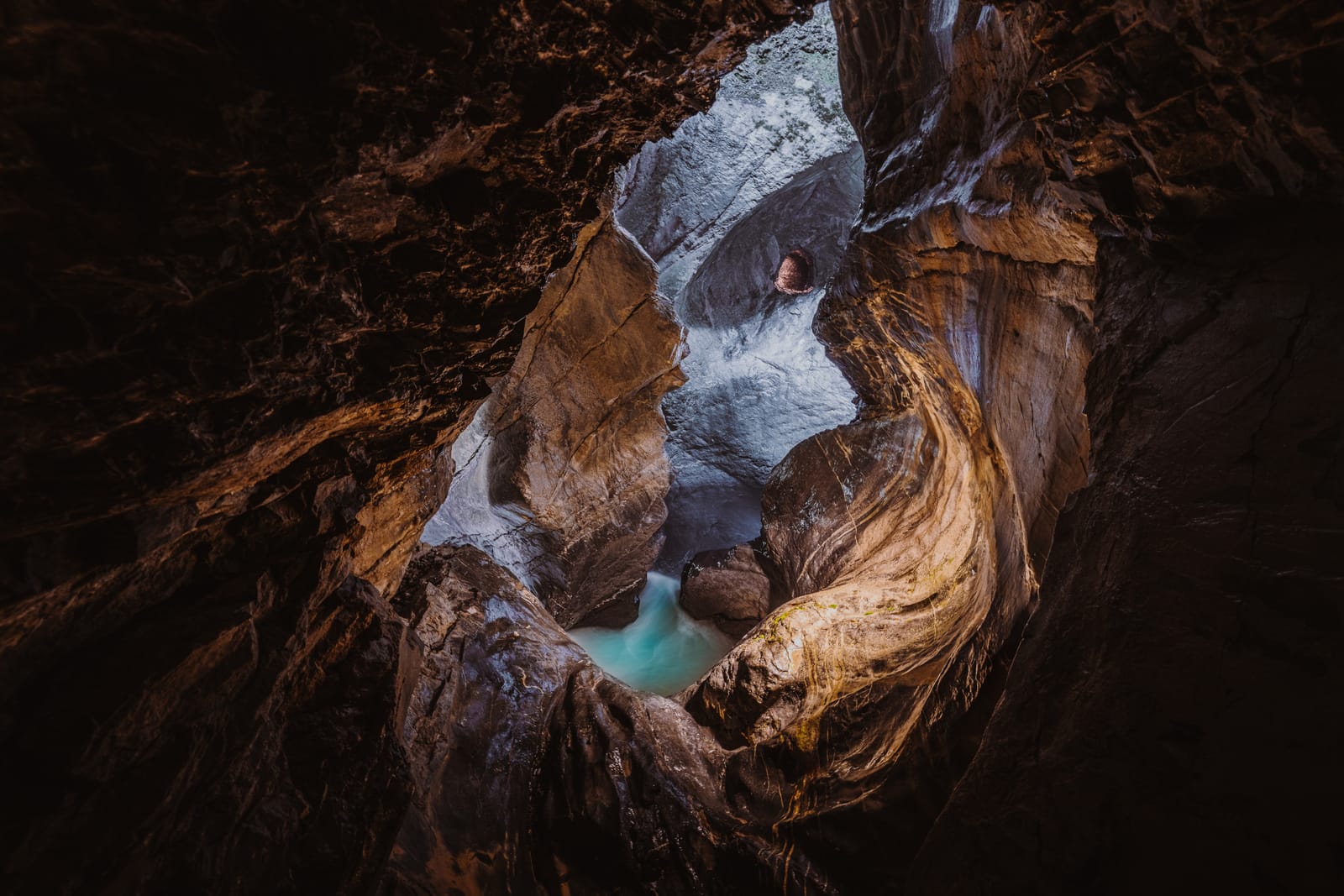 Slot canyon with turquoise pool, shot from above.