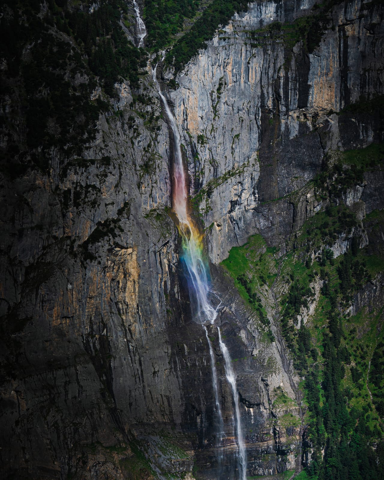 Sheer cliff waterfall with rainbow.