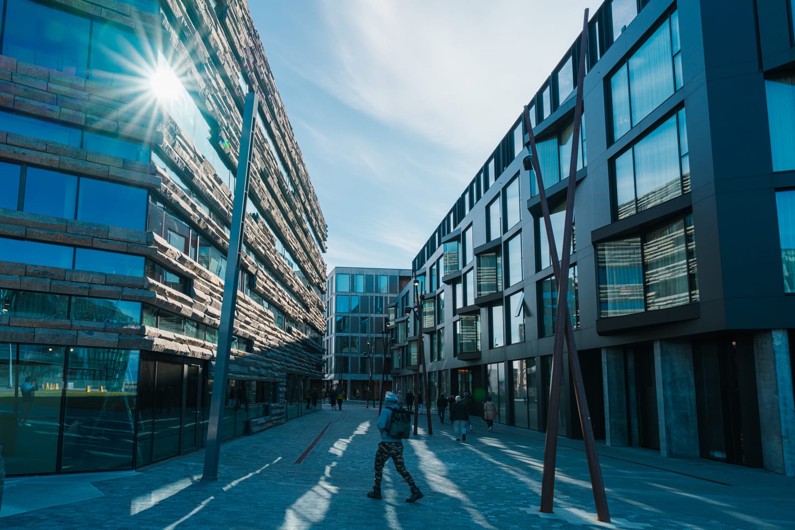 Reykjavík: modern glass architecture street, sun flare, walking figure.