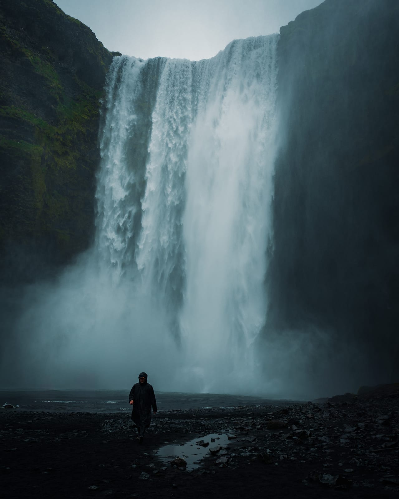 Big waterfall with a lone figure at its base.