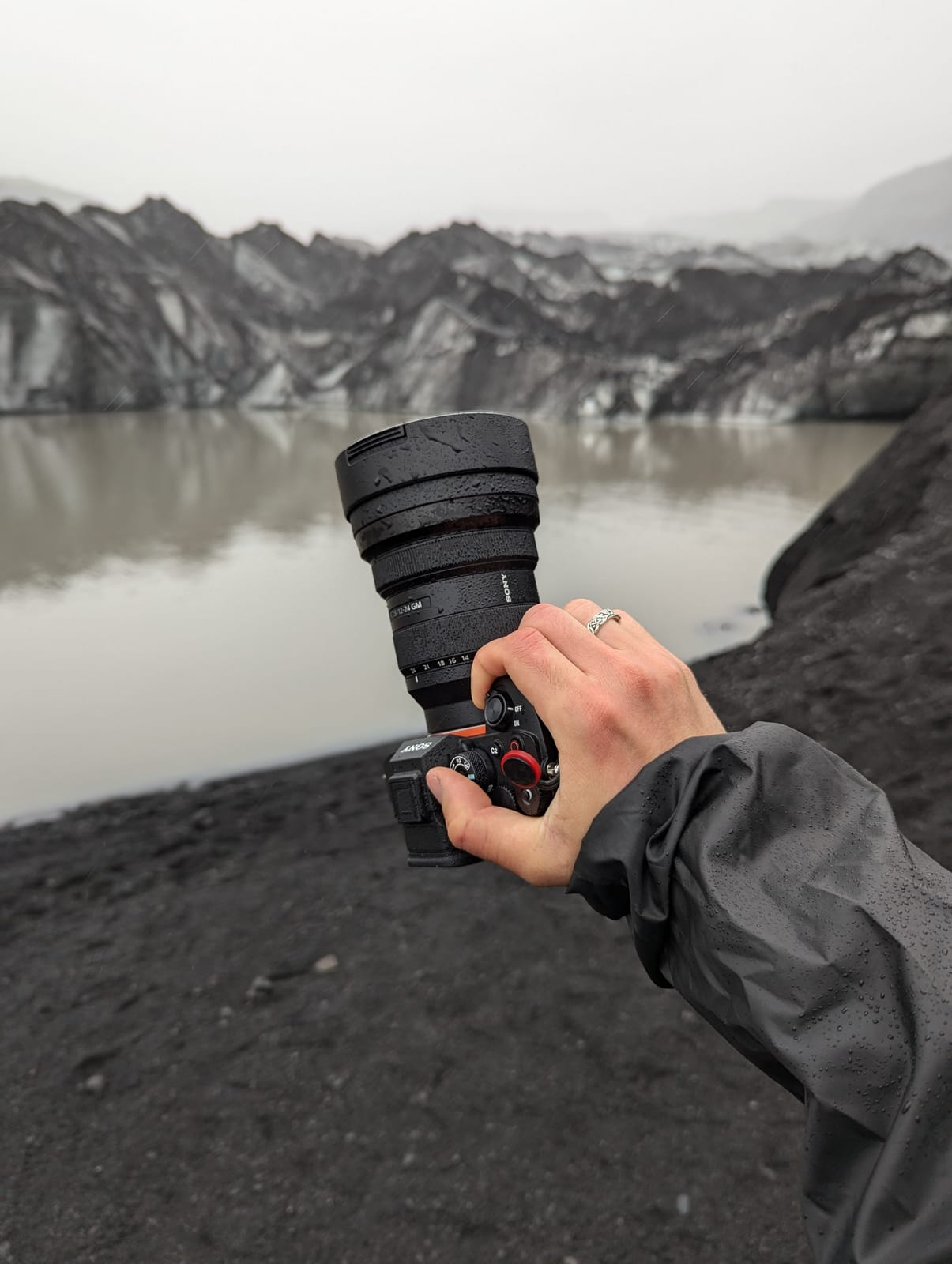 Hand holding the camera with a telephoto lens over a glacier lagoon.
