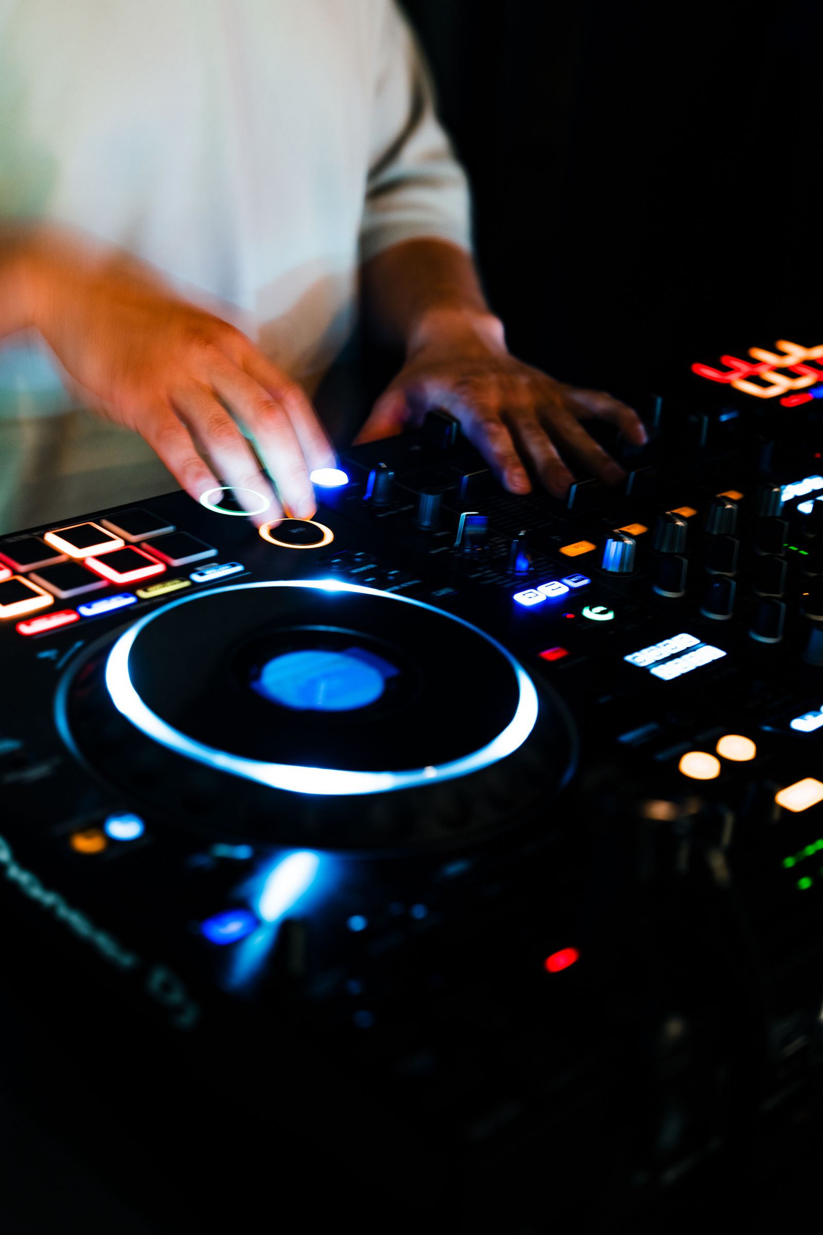 Close-up of the DJ hands on the glowing Pioneer controller at No-Name Lounge.