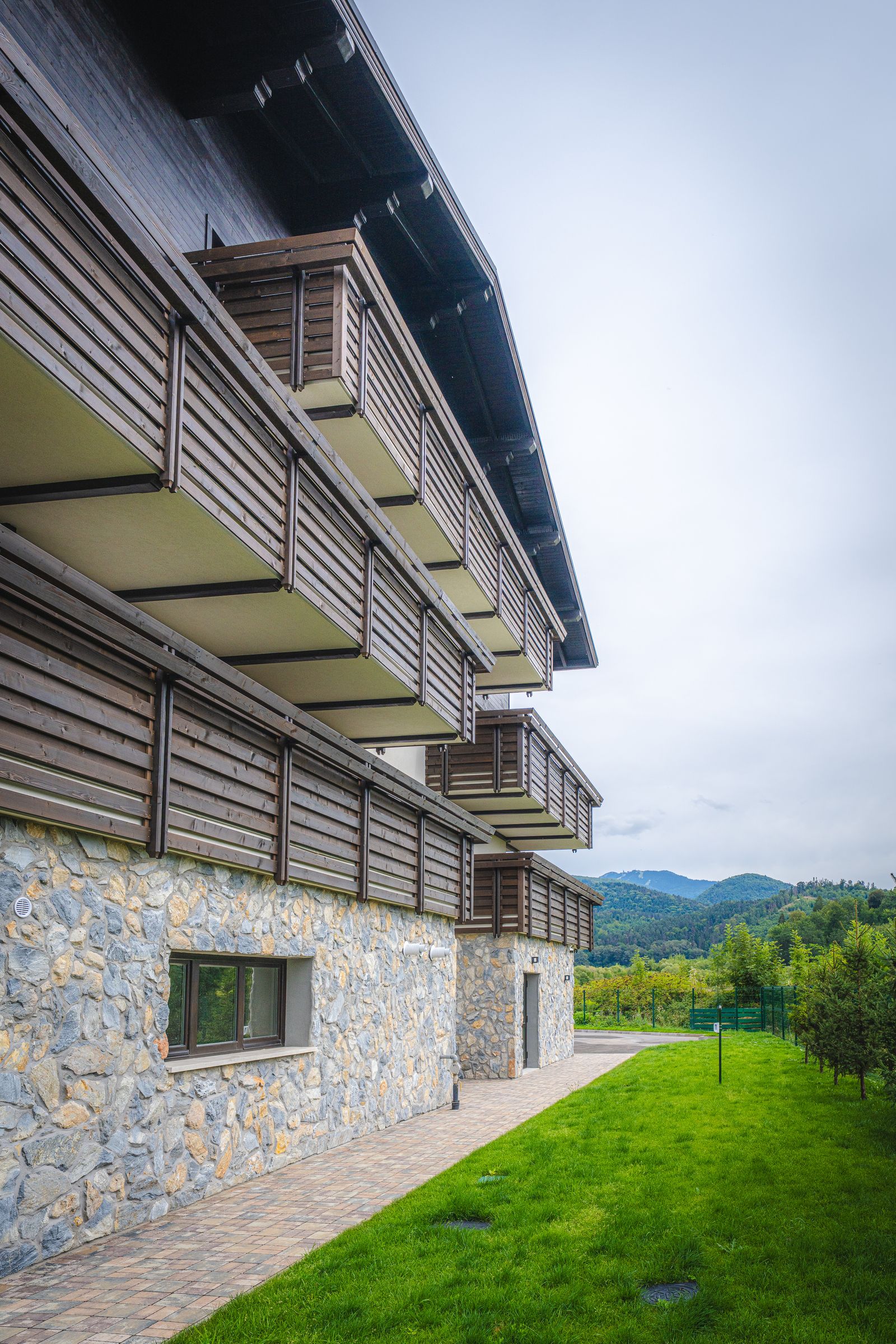 Low-angle view of the stone base and timber balconies of the Teleferic Grand Residence.